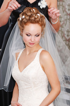 woman in wedding dress having veil adjusted
